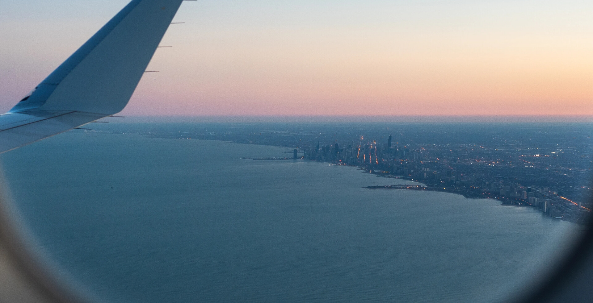 A view of Chicago and Lake Michigan at sunset from an airplane window.