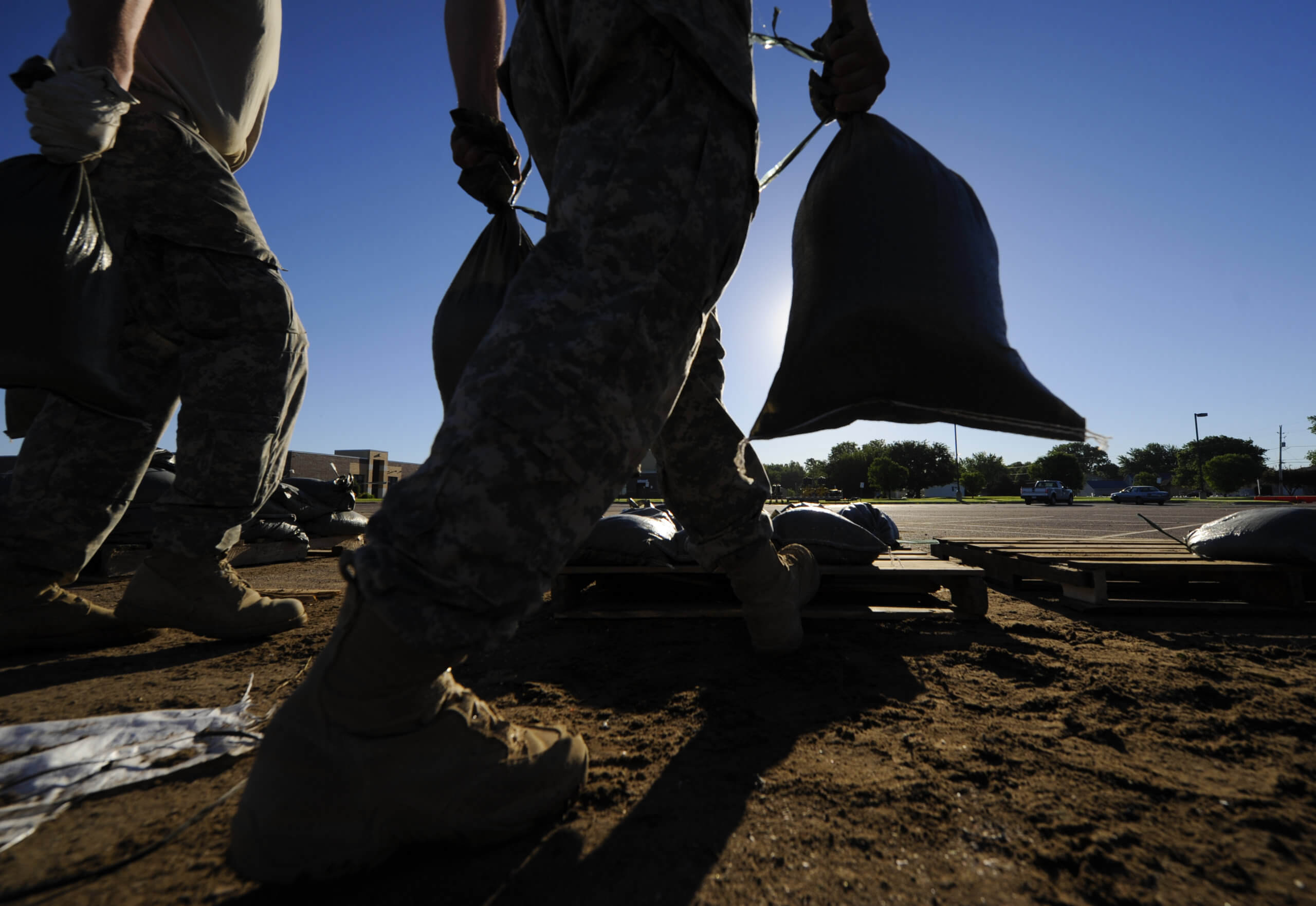 An image from ground-level of National Guard soldiers carrying sandbags.