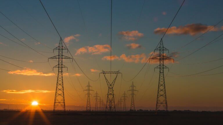 American power transmission lines and power pylons at sunset.