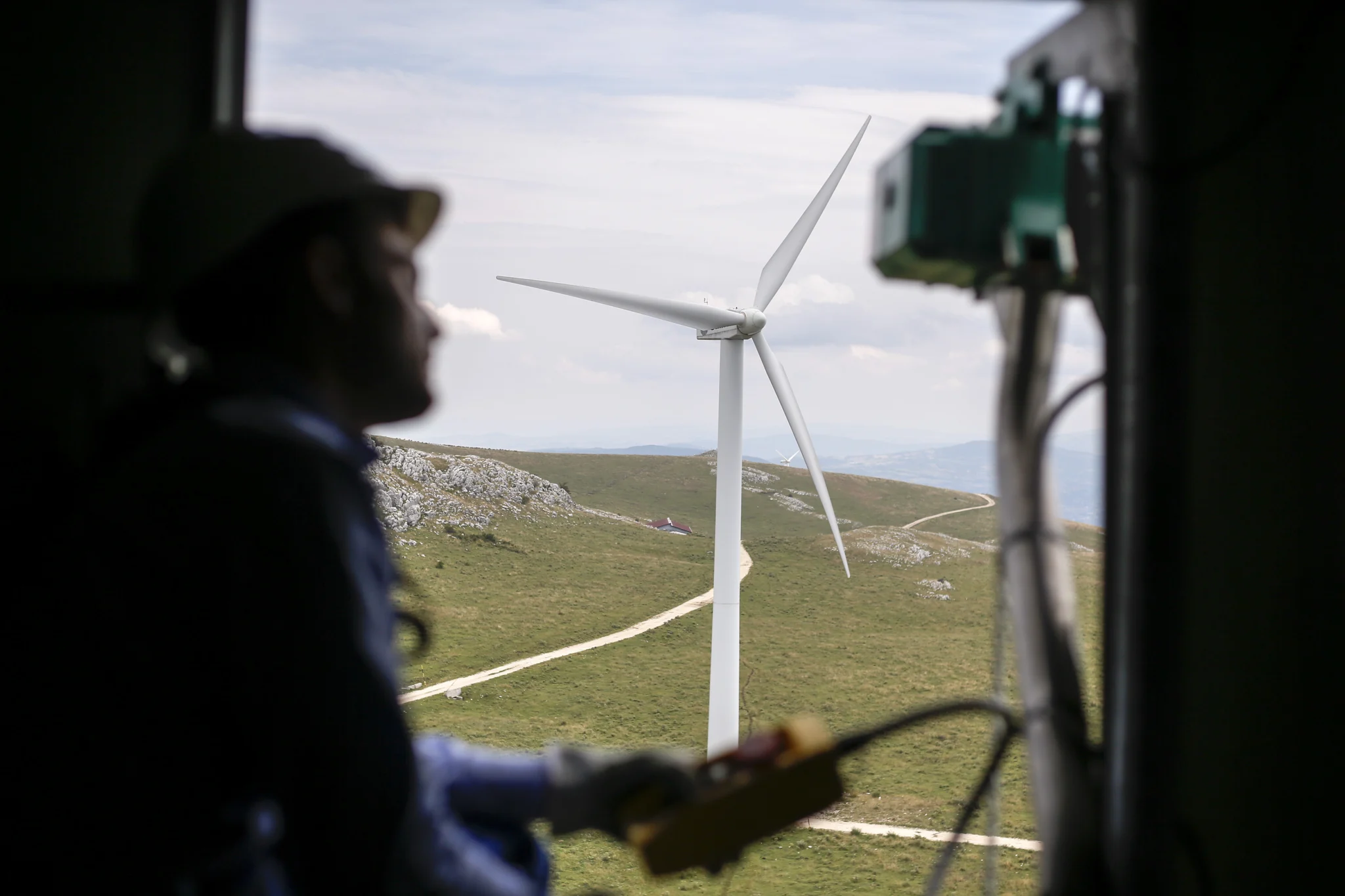Silhouette of an engineer looking out the hatch of a wind turbine while performing maintenance.