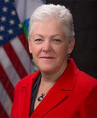 A woman in a red blazer in front of an American flag