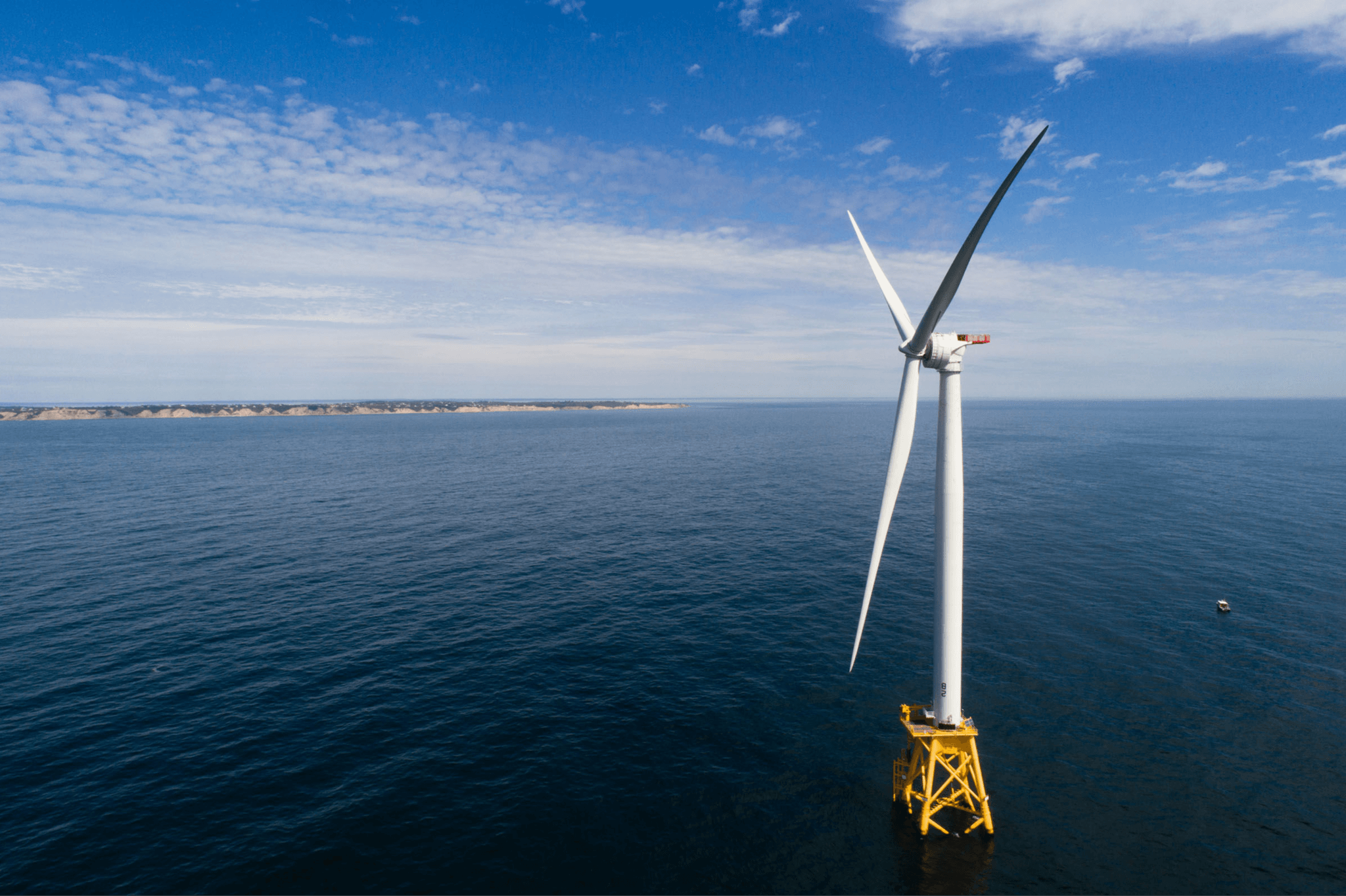 Photo of a off-shore wind turbine in the middle of a body of water.