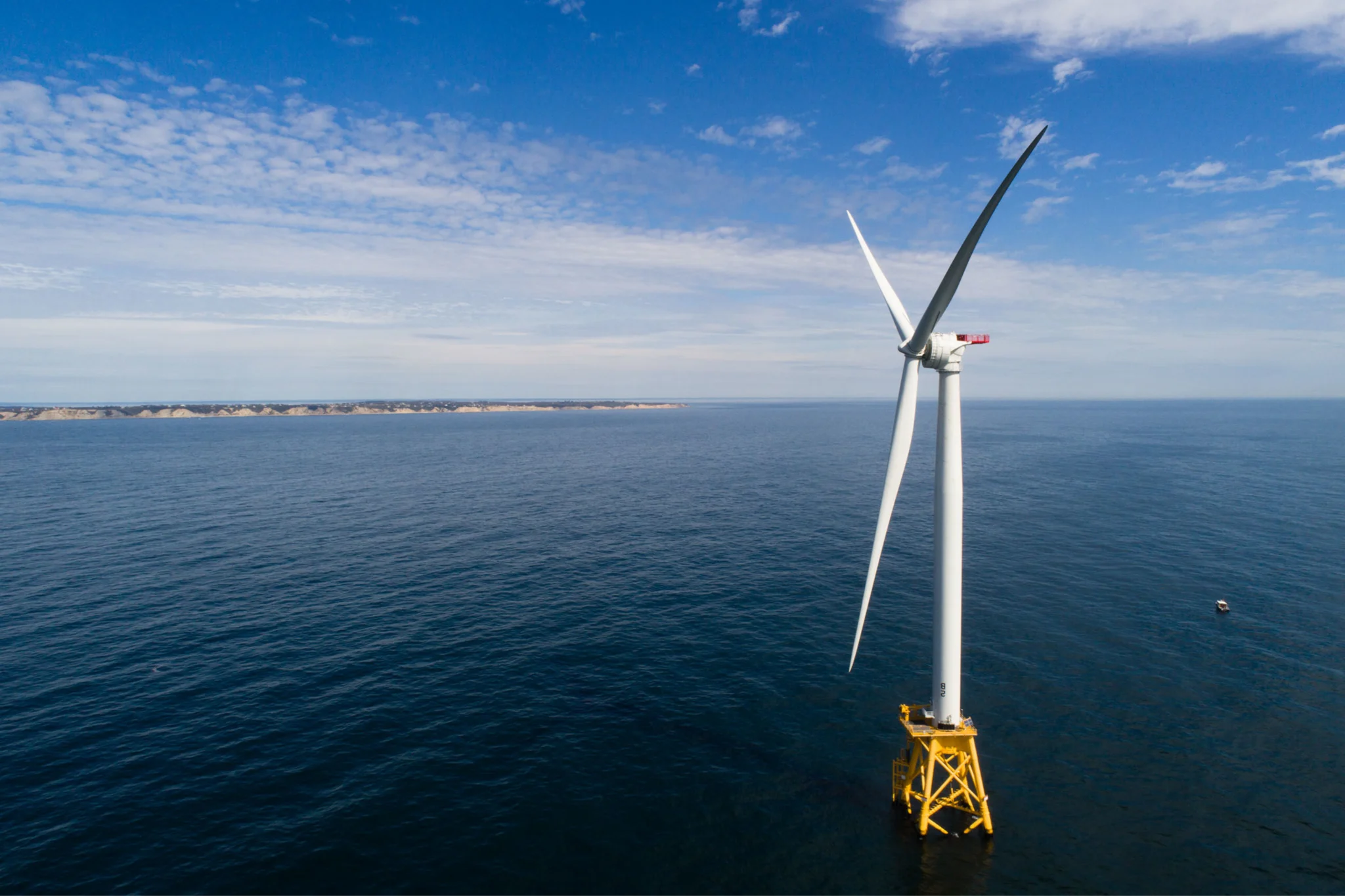 Photo of a off-shore wind turbine in the middle of a body of water.