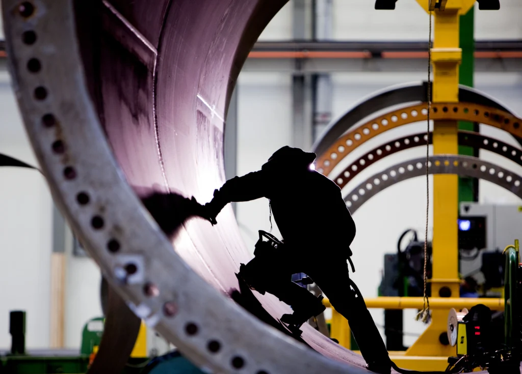 Photo of a manufacturer in shadow working on a wind turbine.