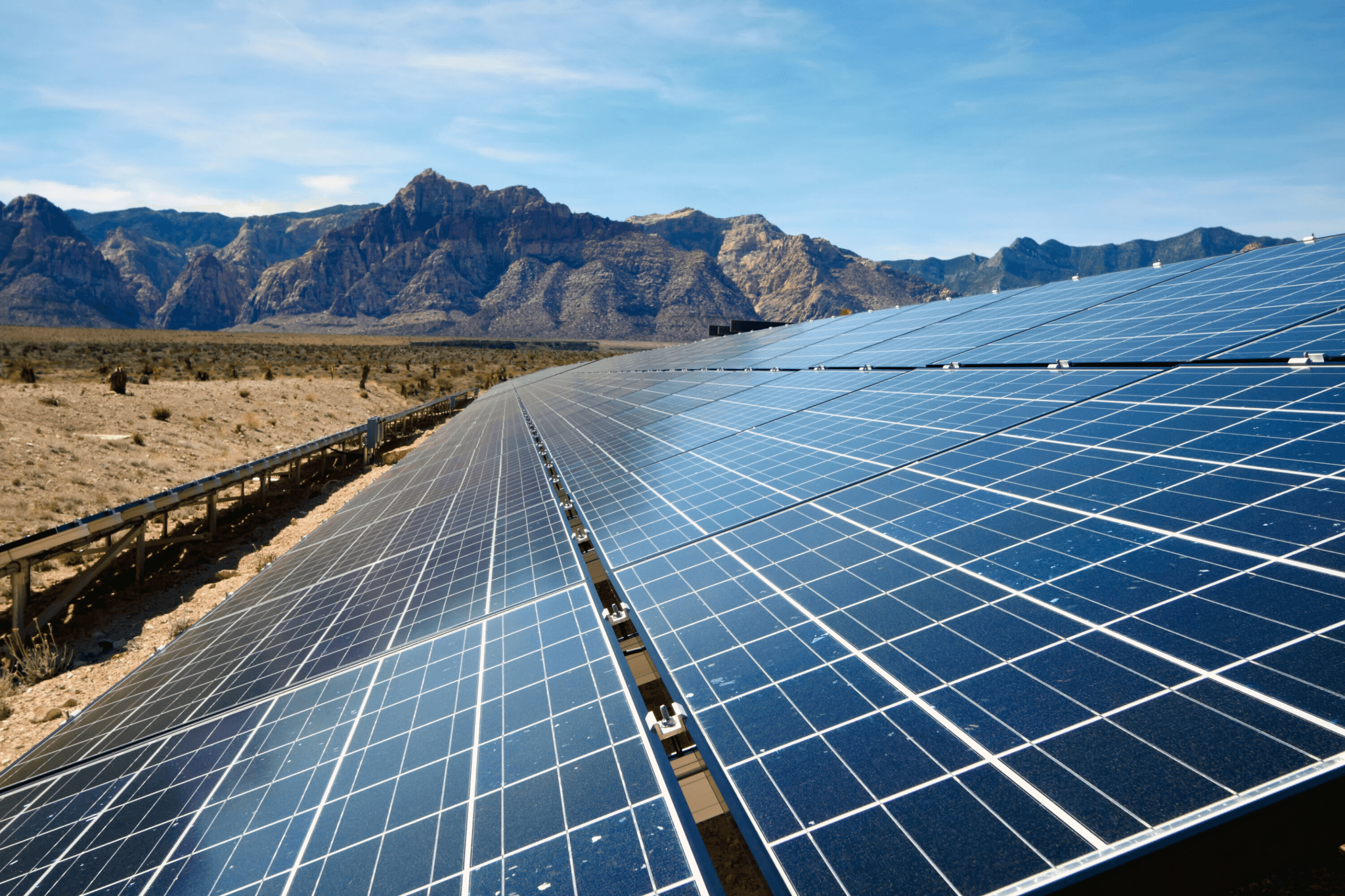 A photo of mountains in the desert with a large solar panel in the foreground