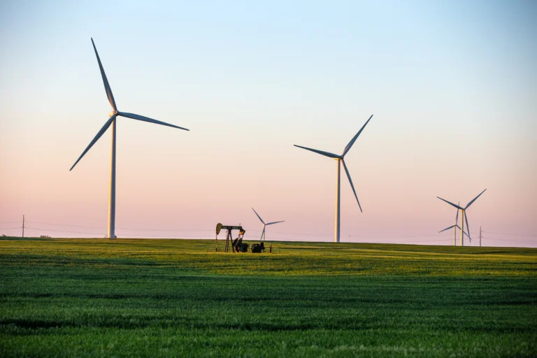 Wind turbines on Kansas prairie with an oil derrick in the foreground.