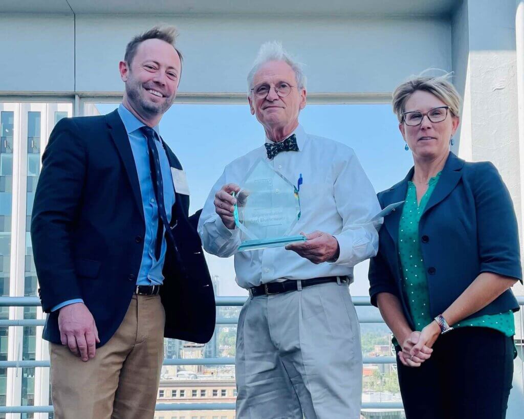 Representative Earl Blumenauer and two associates pose with the Clean Power Champion Award.