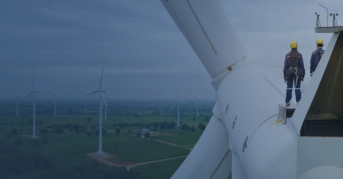 Banner of two wind turbine technicians on top of a turbine looking out over a field.