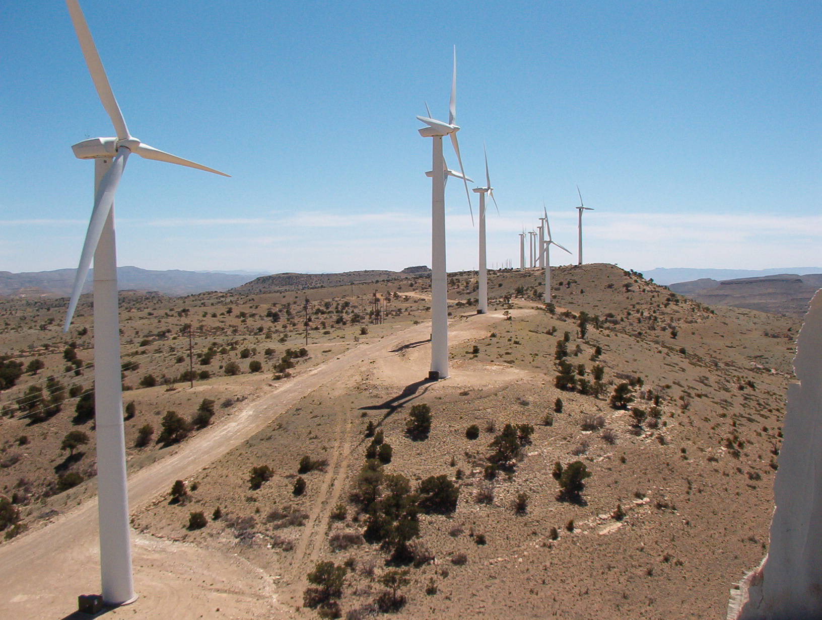 A line of wind turbines on rolling hills of Texas desert.