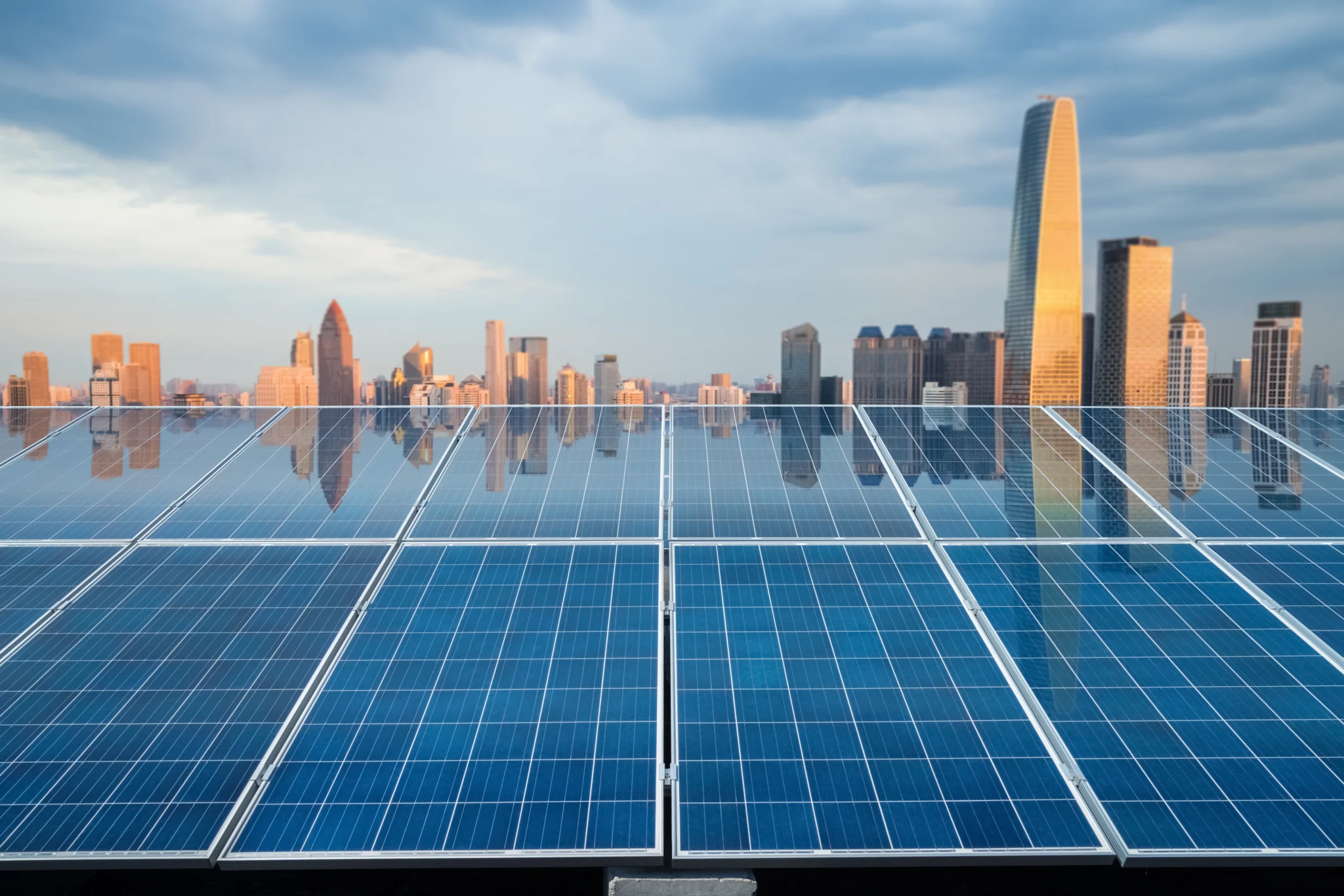 Solar panels with a city skyline reflecting on them.