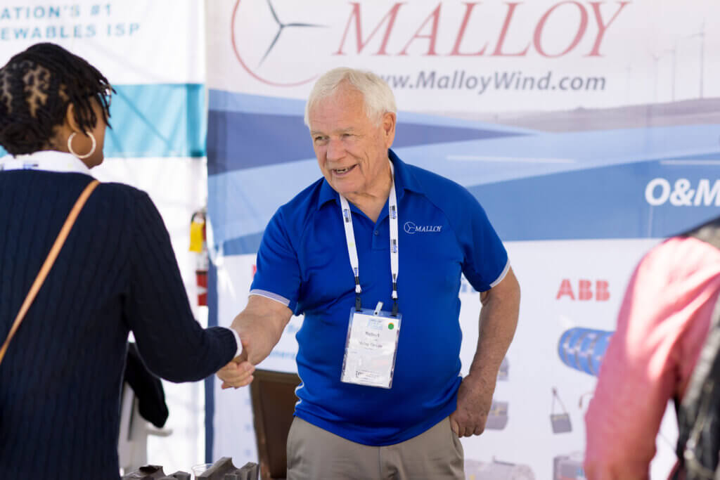 Two ACP conference attendees shake hands in ACP's exhibit hall.