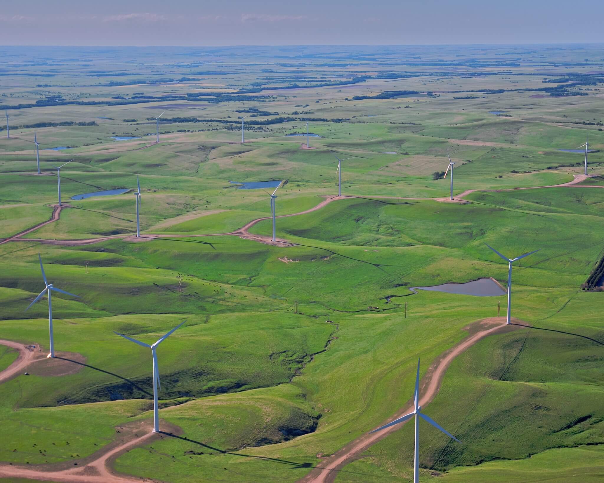 Rolling green hills with wind turbines spaced evenly throughout.