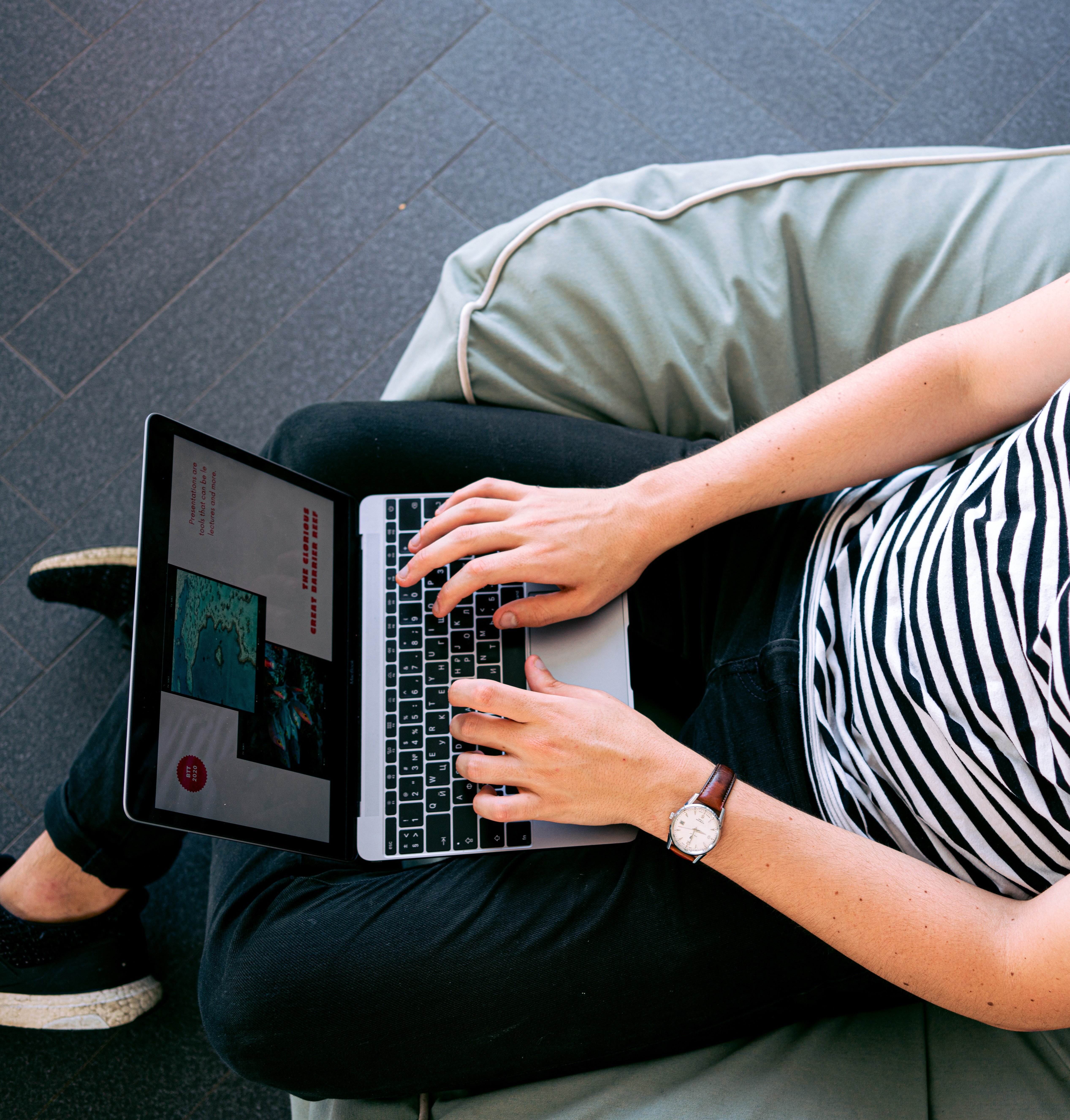a person works on a laptop computer in a bean bag.