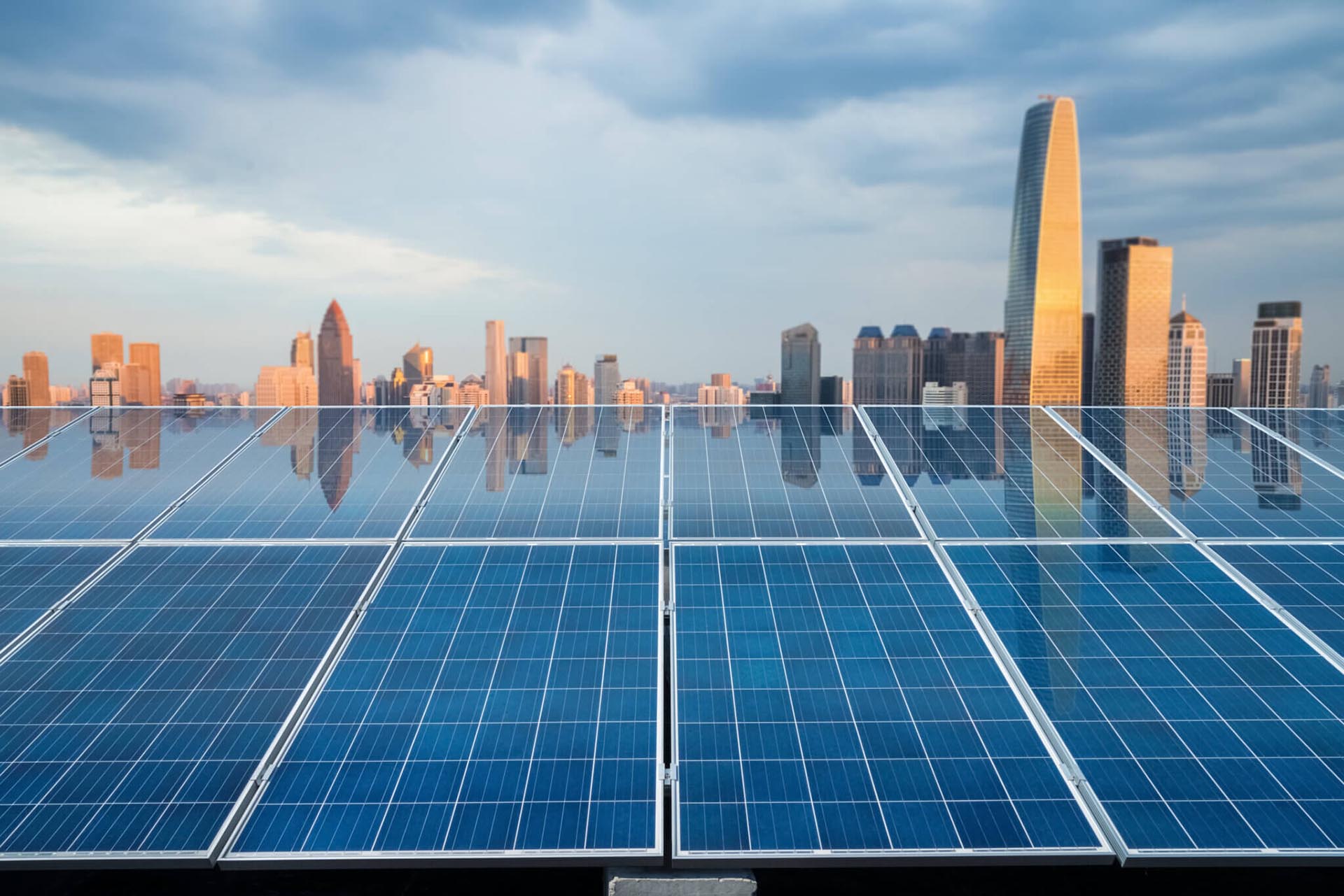 A photograph of solar panels in the foreground with a city skyline in the background.