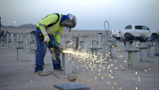 A technician working on a piece of metal with sparks flying.