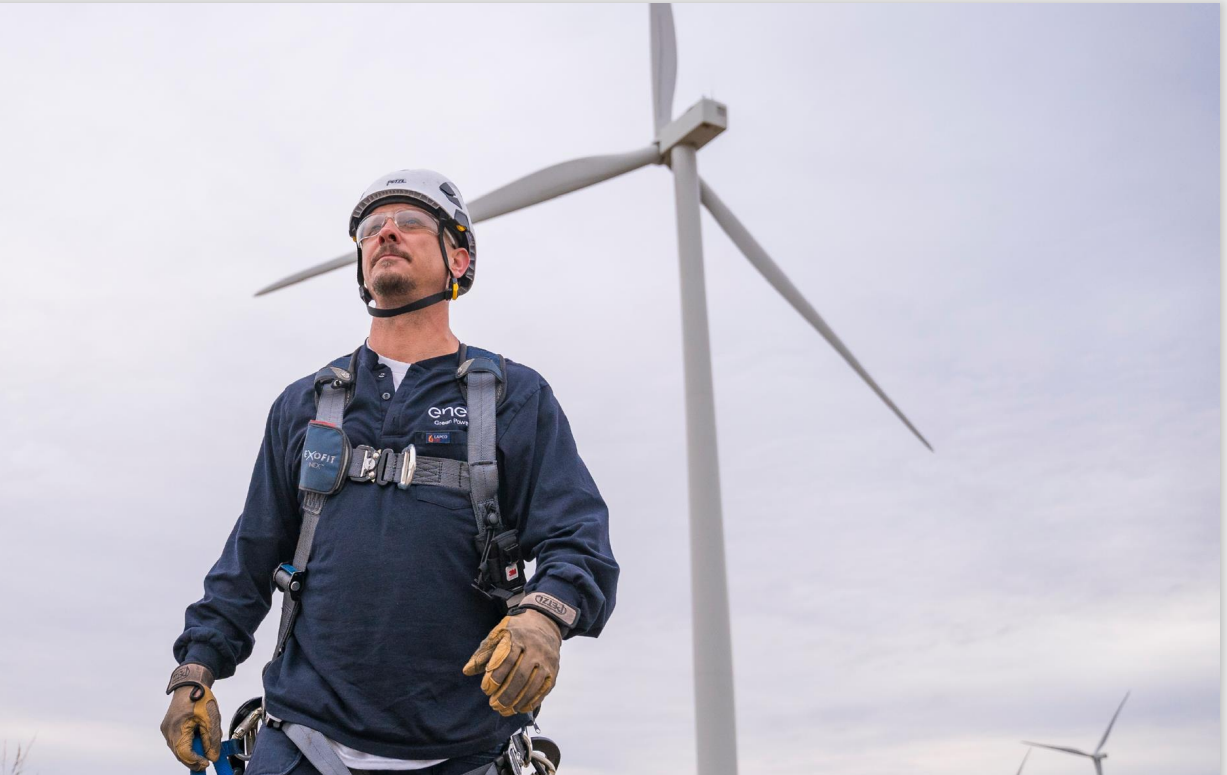 An image of a worker in front of a wind turbine.