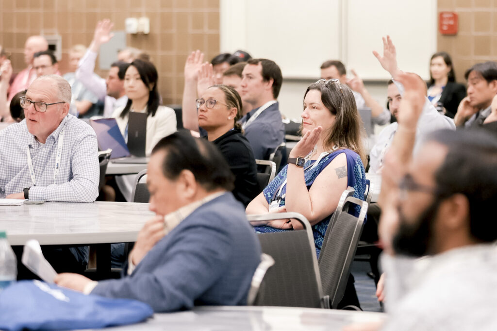 Attendees of an ACP event participating in an extra conference activity raising their hands to ask a question or show support.