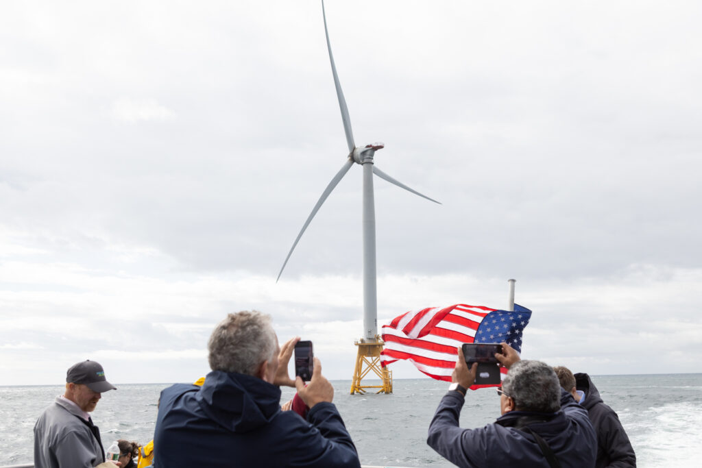 Offshore wind turbines at sea with an American flag in the foreground.