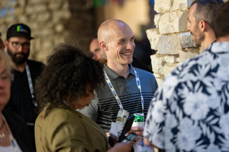Several attendees networking at an ACP event, one of which is sporting a lanyard, an ACP conference sponsorship opportunity.
