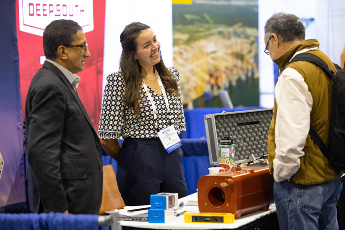 Two exhibitioners at an ACP conference demonstrating their product to a conference attendee.