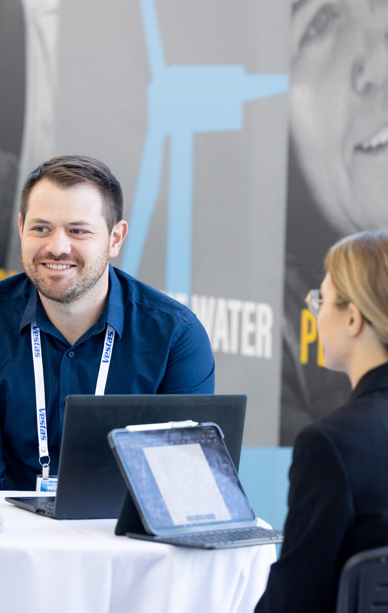 Two attendees of an American Clean Power (ACP) conference fraternizing over laptops, utilizing the Charging Station, a sponsorship opportunity.