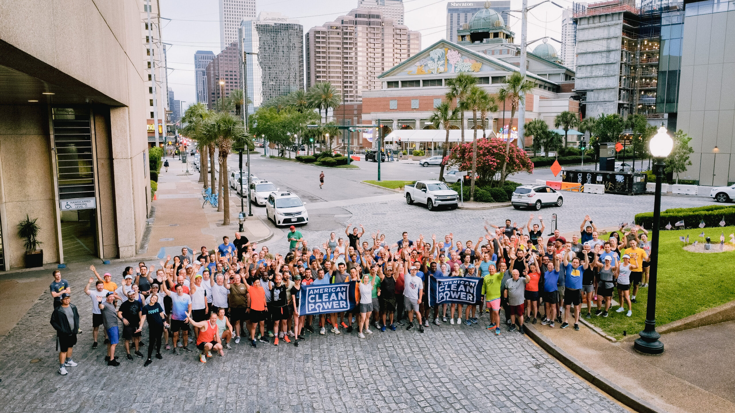 A drone shot of a crowd on a New Orleans street gathered for the 5k fun run at CLEANPOWER holding American Clean Power Flags