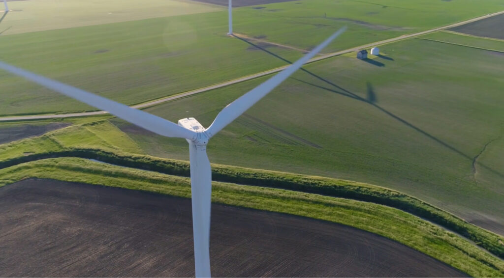 Aerial shot of a wind turbine above a grassy field.