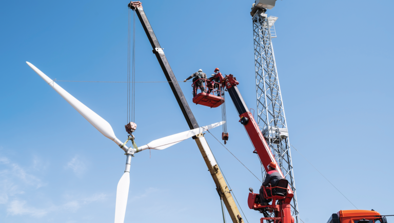 Construction of a wind power plant. Installers use a truck crane and aerial platform to raise the wind turbine rotor. Photo taken on a sunny summer day